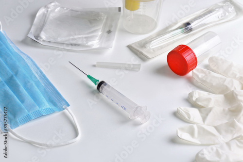 close on a a syringe with needle among pharmacy equipment and a face mask