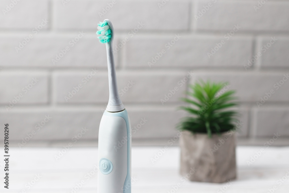 Modern electric toothbrush on white bricks background. Close up photo. oral hygiene accessories Modern electric toothbrush on white bricks background. Close up photo. oral hygiene accessories