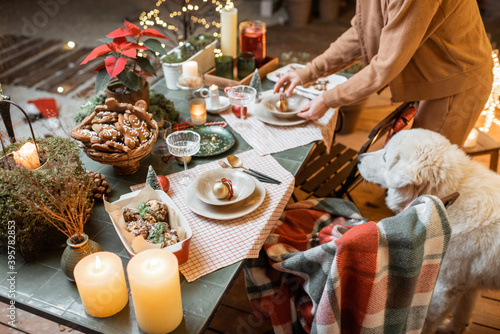 Woman serving and decorating a festive dinner table on the christmas eve outdoors on the terrace photo