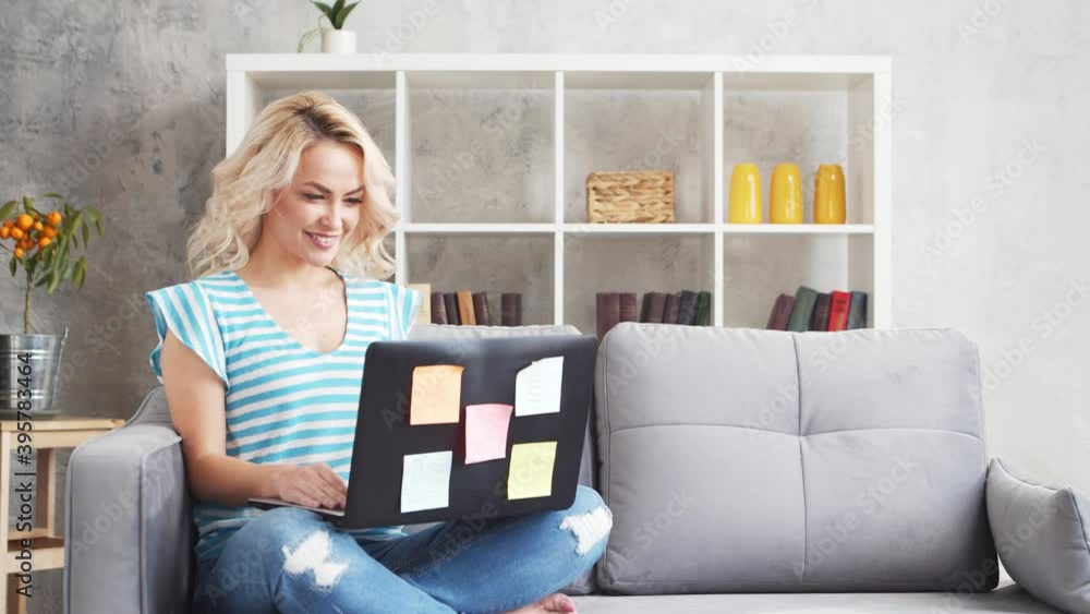 Young and attractive woman works at home using laptop computer. Freelancer or student on the couch. Young and attractive woman works at home using laptop computer. Freelancer or student on the couch.
