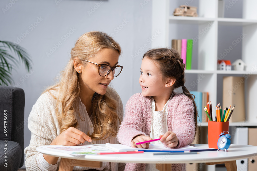Fototapeta premium girl drawing pictures with colorful pencils while visiting psychologist