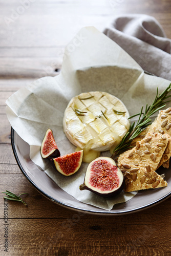 Baked Brie cheese with honey and fresh figs, gallettes and nuts on wooden table. Selective focus photo