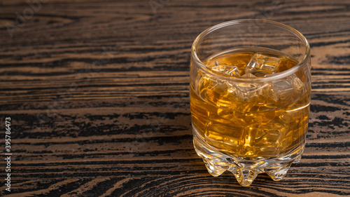 Glass of scotch whiskey and ice on wooden table.A glass of hard liquor. Close up whiskey in a glass tumbler
