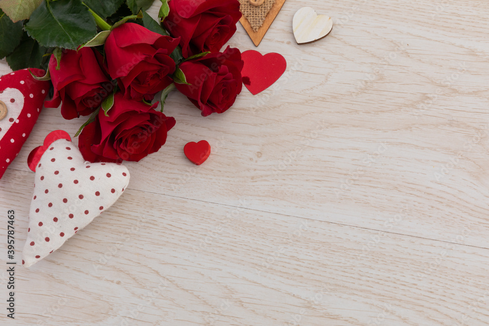 Fototapeta premium Bunch of red roses and hearts lying on wooden background