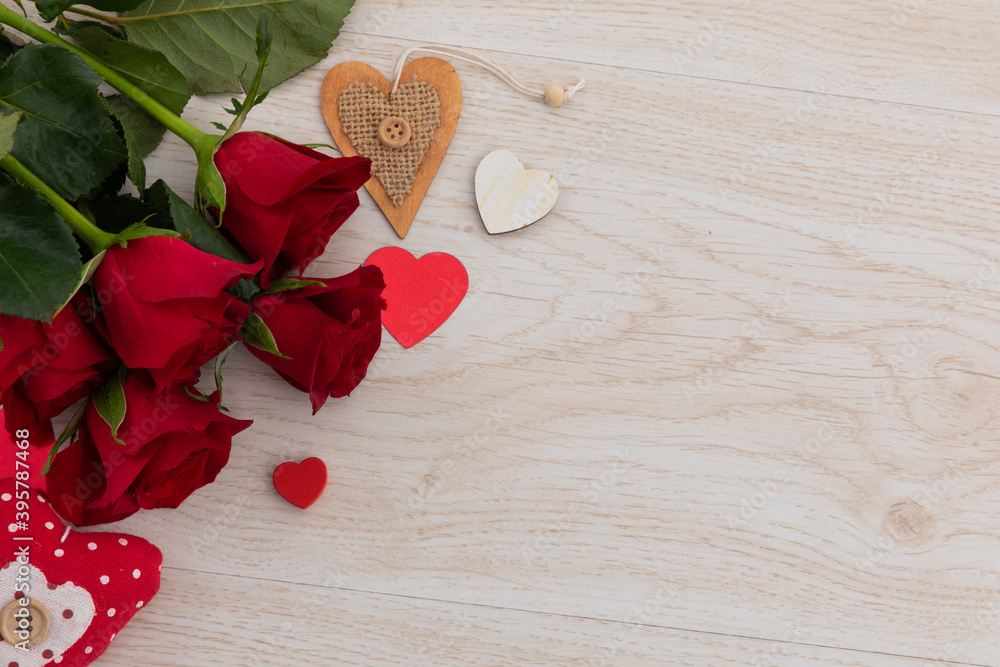 Fototapeta premium Bunch of red roses and hearts lying on wooden background
