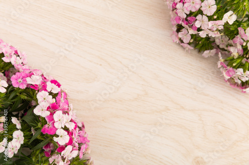 Two bunches of pink flowers in corners on wooden background