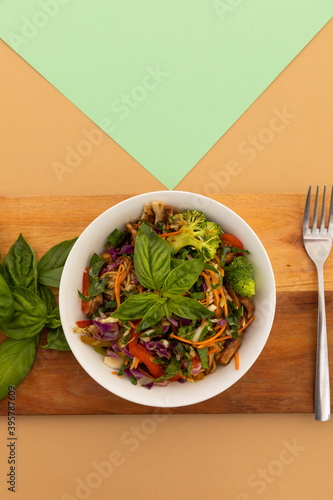 High angle view of bowl with salad and basil leaves on board