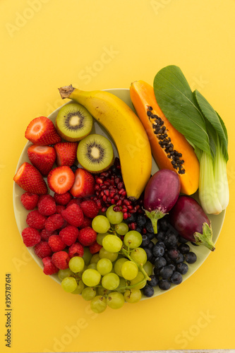 High angle view of bowl of banana, berries, grapes and baby aubergines