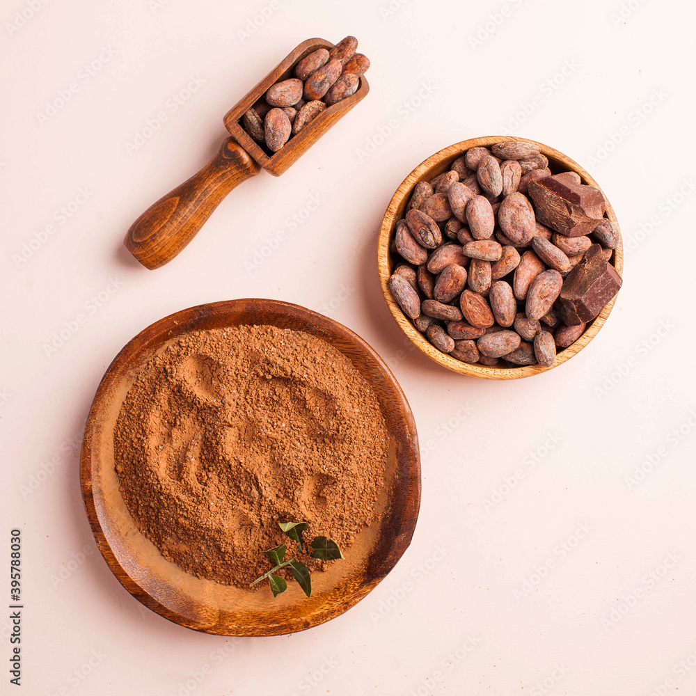 Flatlay Cocoa beans, cocoa powder, raw chocolate on a pink background. The concept of healthy eating. Flatlay Cocoa beans, cocoa powder, raw chocolate on a pink background. The concept of healthy eating.