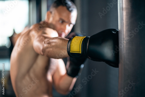 close up of muscular boxer male workout and training with punching bag in gym