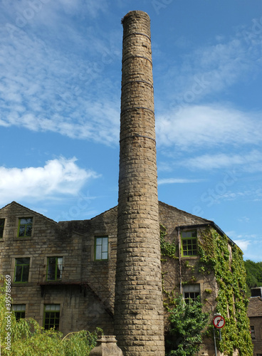 old mill building and tall chimney with blue cloudy sky in hebden bridge west yorkshire