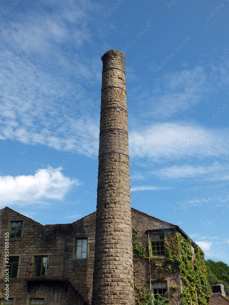 old mill building and tall chimney with blue cloudy sky in hebden bridge west yorkshire old mill building and tall chimney with blue cloudy sky in hebden bridge west yorkshire