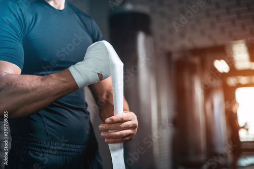 close up of boxer man bandage hand and preparing for training or fighting in gym