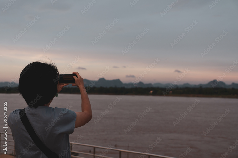 rear view of woman using smartphone to shoot picture of mekong river during vacation