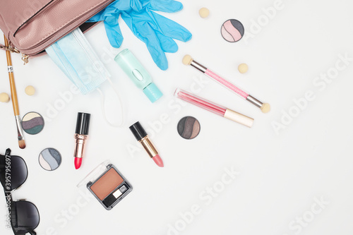 womens handbag with cosmetics and medical mask sanitizer, covid-19, flat lay