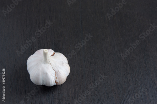 unpeeled ripe garlic on a dark wooden background