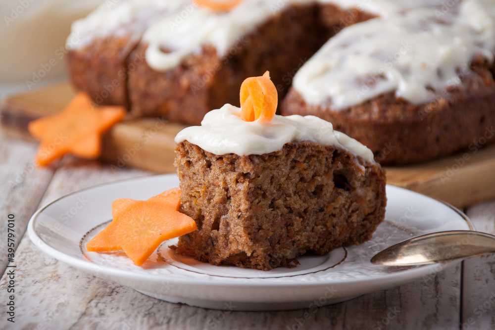 Piece of carrot cake on a white leaf plate with carrot decor