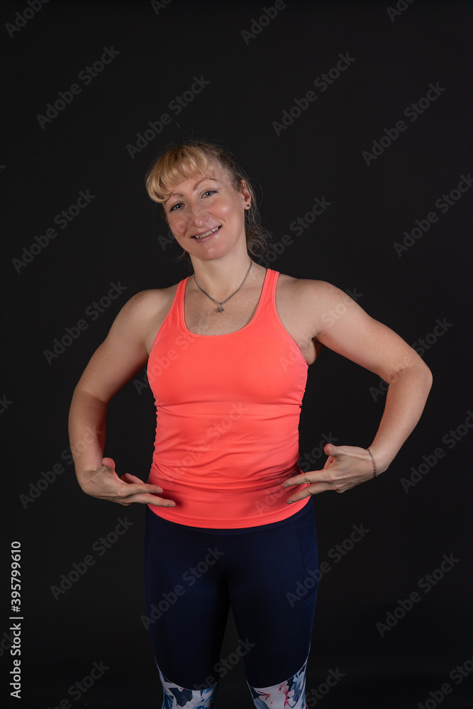 Fitness on a step platform with a barbell with dumbbells. Going in for sports on a black background Joyful looking at the camera Fitness on a step platform with a barbell with dumbbells. Going in for sports on a black background Joyful looking at the camera