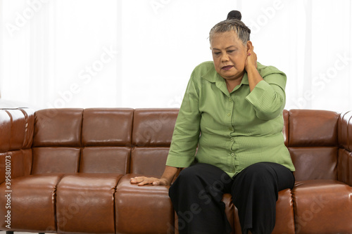 senior asian fat woman suffering from neck pain on sofa