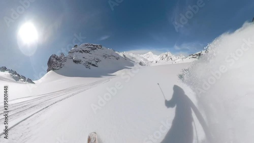 POV: Shredding virgin powder snow while riding off trail in the scenic white Canadian Rockies. Cool first person shot of snowboard touring in the Rocky Mountains on a picturesque sunny winter day. photo