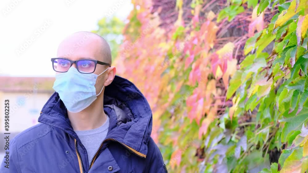 young man in a jacket and a medical white mask walks the streets of a European city, the concept of a business trip, travel in the fall, the period of the covid-19 coronavirus pandemic young man in a jacket and a medical white mask walks the streets of a European city, the concept of a business trip, travel in the fall, the period of the covid-19 coronavirus pandemic