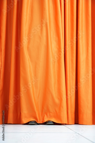 Person Hiding Behind Orange Curtain