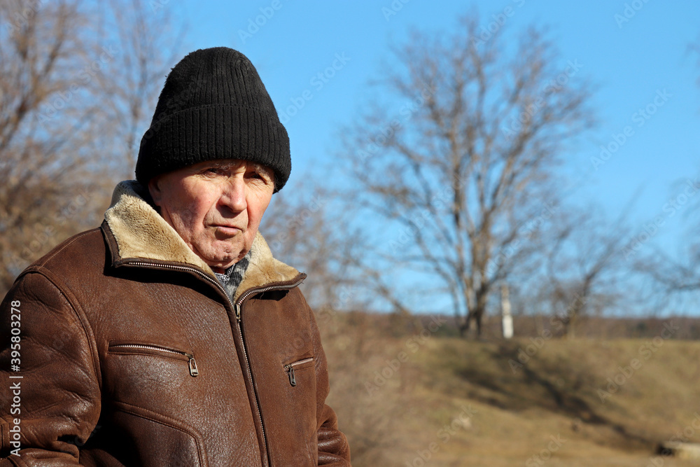 Portrait of dissatisfied elderly man in winter weather. Concept of old age, life in village