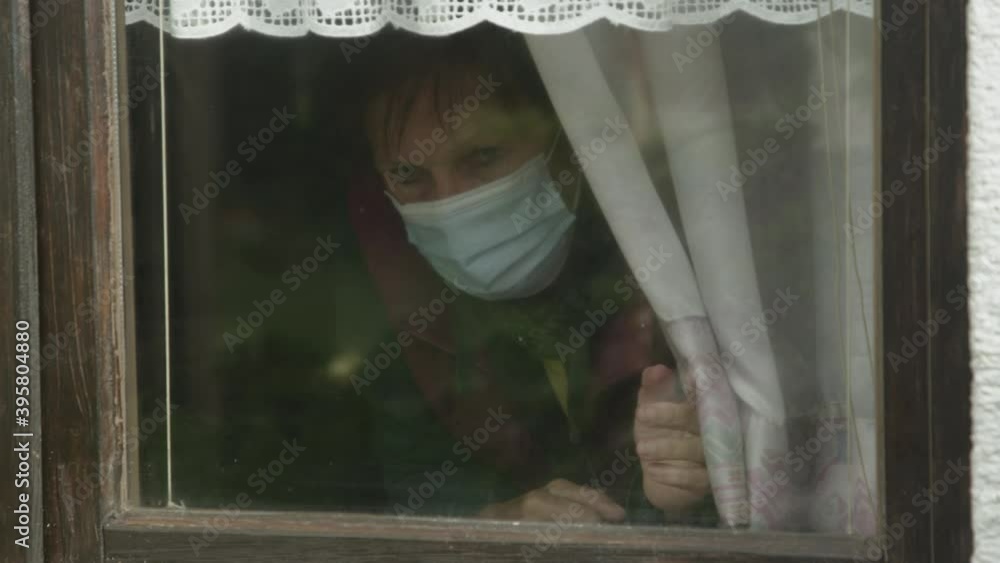 SLOW MOTION CLOSE UP: Frightened elderly lady moves the curtain to observe the neighborhood during covid lockdown. Lonely senior woman opens curtains to look out the window during coronavirus pandemic SLOW MOTION CLOSE UP: Frightened elderly lady moves the curtain to observe the neighborhood during covid lockdown. Lonely senior woman opens curtains to look out the window during coronavirus pandemic