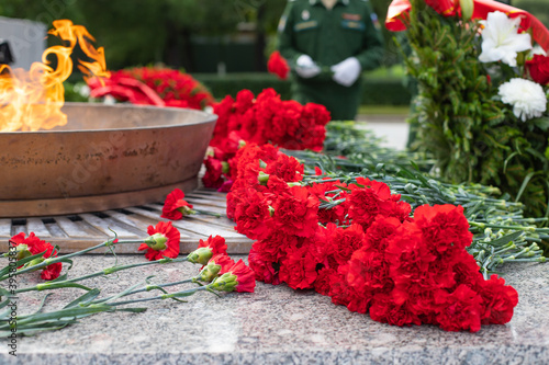Laying a red carnation in memory of the dead. red carnations on a granite gravestone.memorial complex with eternal flame in honor of the memory of those killed in world war. Selective focus