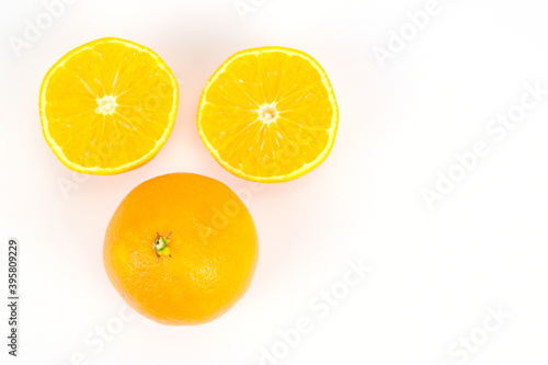 An overhead view of one unpeeled tangerine and the other cut into two equal halves. Isolated over white background.