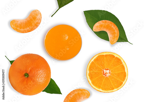 ripe and sweet tangerine with green leaves and a glass of juice on a white background