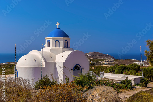 A view of a blue-domed church close to the settlement of Akortiri in Santorini in summertime