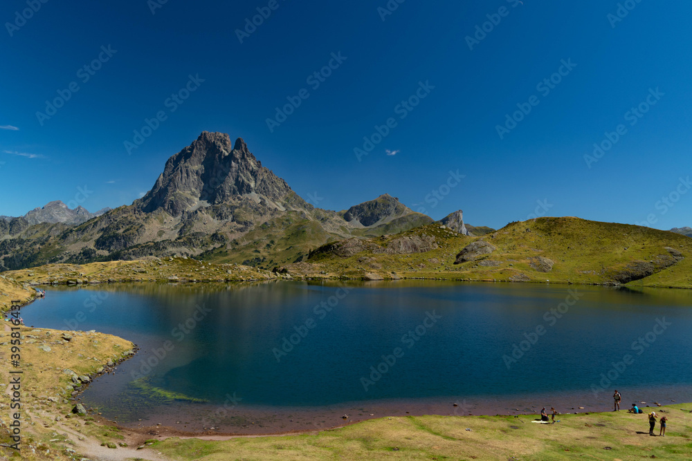 Bathers' pools on the shores of Ayous mountain lake with the mountains and the top of Midi d'Ossau in the background