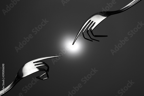 Φωτογραφία Closeup of metal forks with bent tines shaped like fingers touching a bright igh