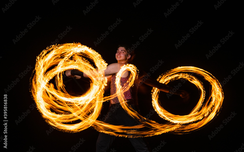 Happy male fire dancer twirl burning baton creating sparkling trails in motion dark outdoors, twirler Happy male fire dancer twirl burning baton creating sparkling trails in motion dark outdoors, twirler