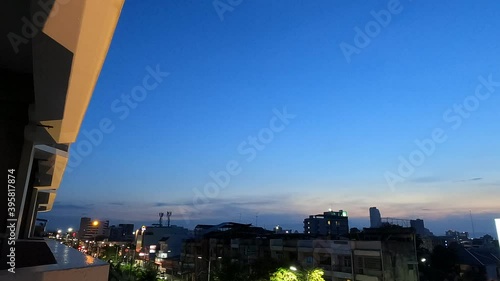 Aerial view from resort hotel balcony of City night life scene with street light n business cityscape building at colorful evening on dramatic blue sky n dark clouds, 4k cinemagraphs b-roll TimeLapse photo