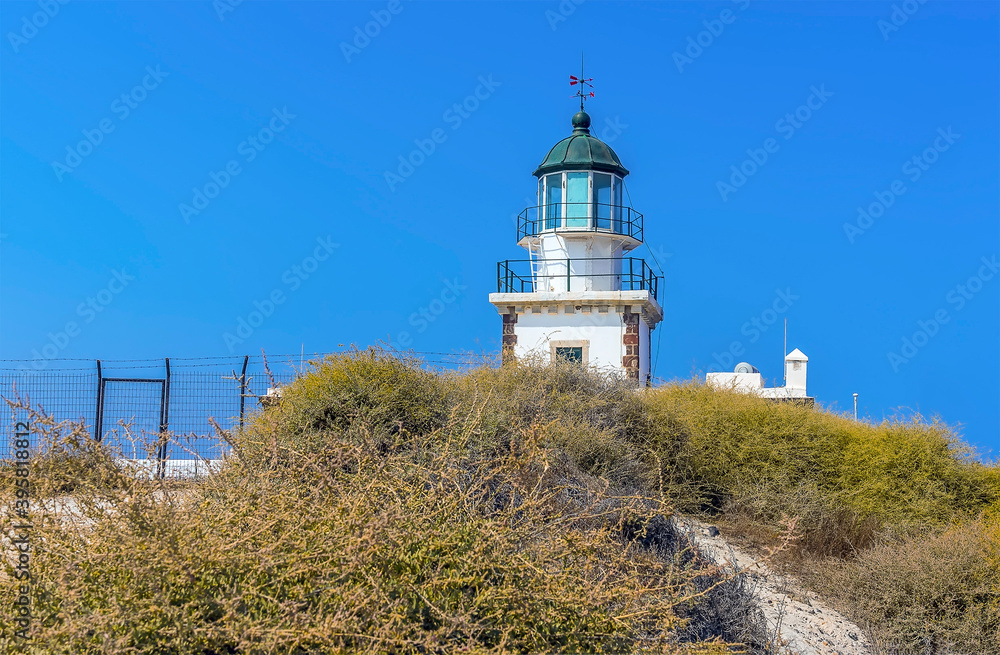 The lighthouse at Akortiri peeps up above a dune in Santorini in summertime