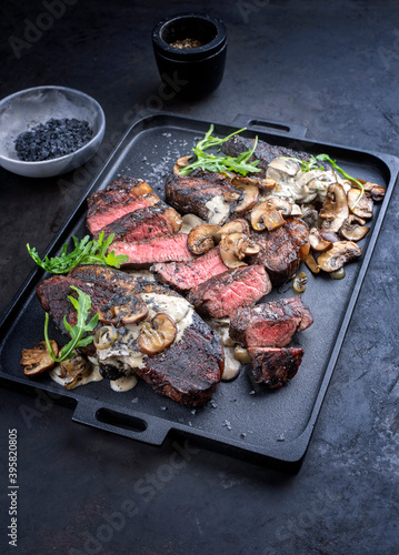 Modern style barbecue dry aged wagyu Brazilian picanha steaks from the sirloin cap of rump beef sliced and served cream sauce and mushrooms as close-up on a design tray