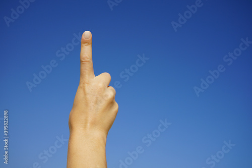 women's hands show the number one against a cloudless blue sky