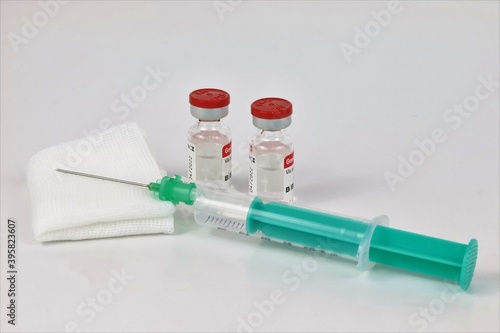 vacuna con jeringa verde y gasa de algodón