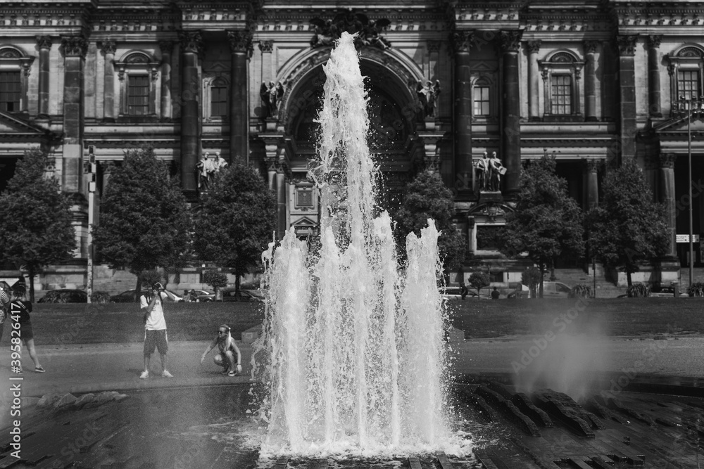 Fototapeta premium black and white fountain in a park with a building in a background
