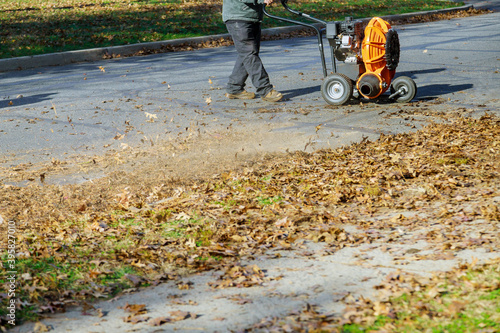 Man operating cleaning the sidewalk with a leaf blower