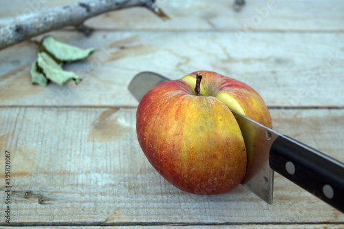 cut red apple with a knife on a wooden table