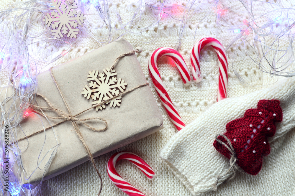 New year's gift, a caramel heart on a knitted white jacket and a multi-colored garland, top view-the concept of waiting for pleasant holidays New year's gift, a caramel heart on a knitted white jacket and a multi-colored garland, top view-the concept of waiting for pleasant holidays