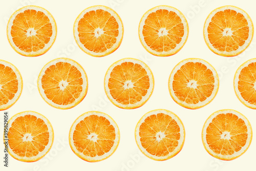 The pattern of fresh orange slices on light beige background. Colorful fruit slices top view.