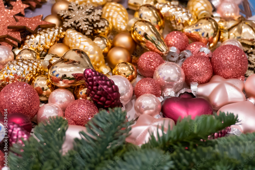 Focus on Christmas decorations in golden and pink / rose colors, in the foreground a wreath of pine needles with blur / bokeh