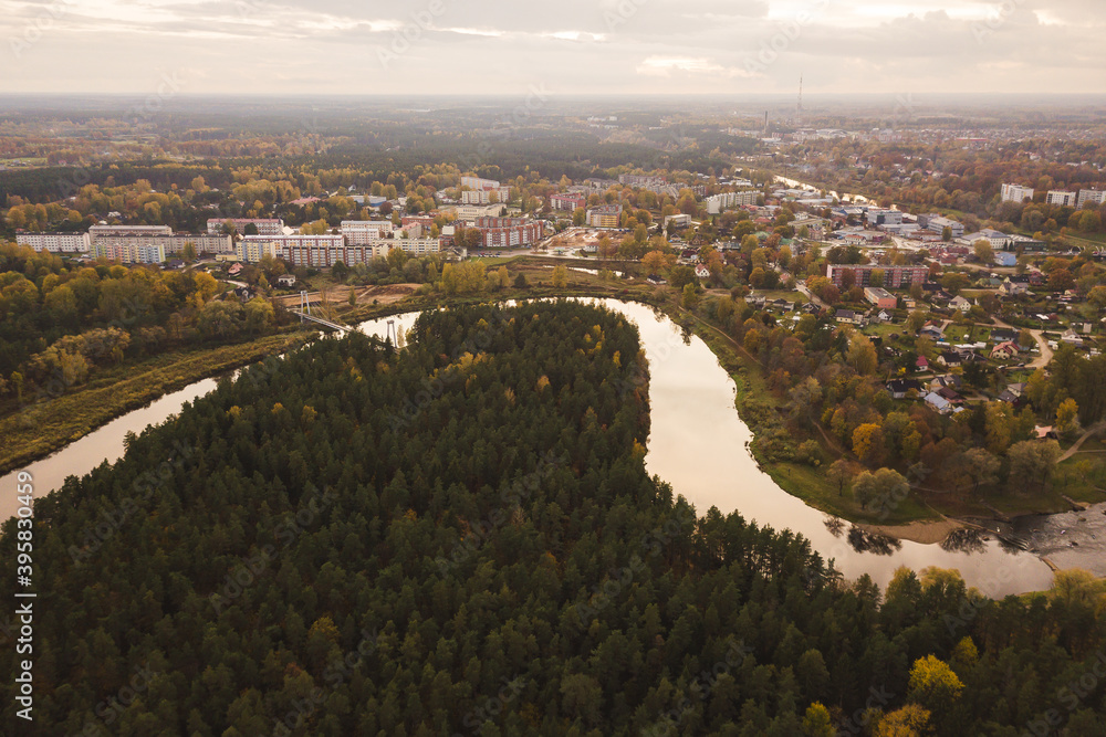 view from above drone shot of a city Valmiera, Latvia, autumn fall cloudy day river Gauja river turns green forest woods park 