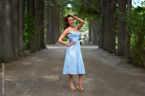 a girl in a blue dress walks in the Park.