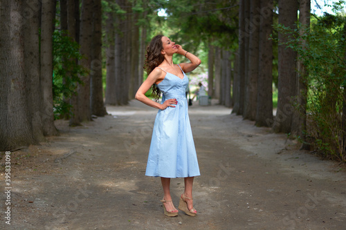 a girl in a blue dress walks in the Park.