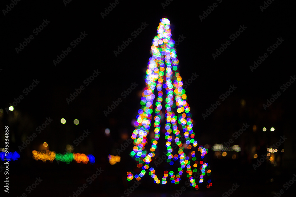 silhouette of colorful wreaths in the shape of a Christmas tree with space for text. Blurred abstract bright spot lights isolated on dark background. new year and christmas bright background silhouette of colorful wreaths in the shape of a Christmas tree with space for text. Blurred abstract bright spot lights isolated on dark background. new year and christmas bright background